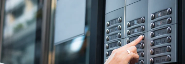 Hand drückt Klingel an Gegensprechanlage